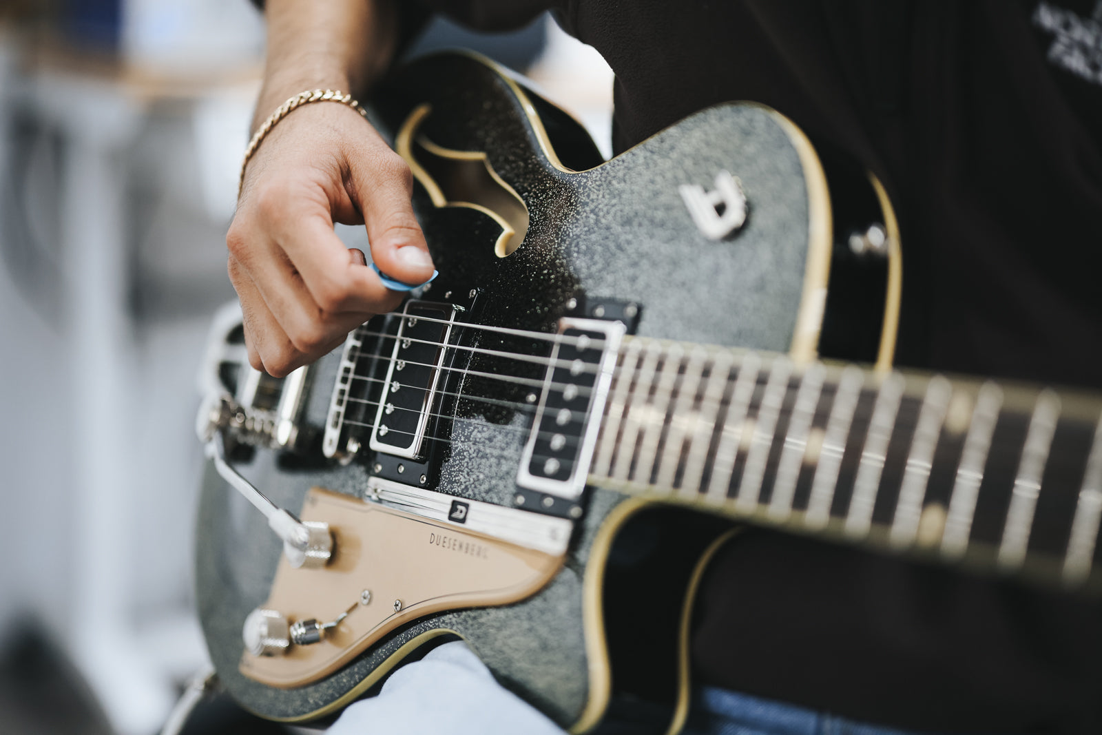 Macro image of electric guitar strings with a hand playing on a black sparkle guitar