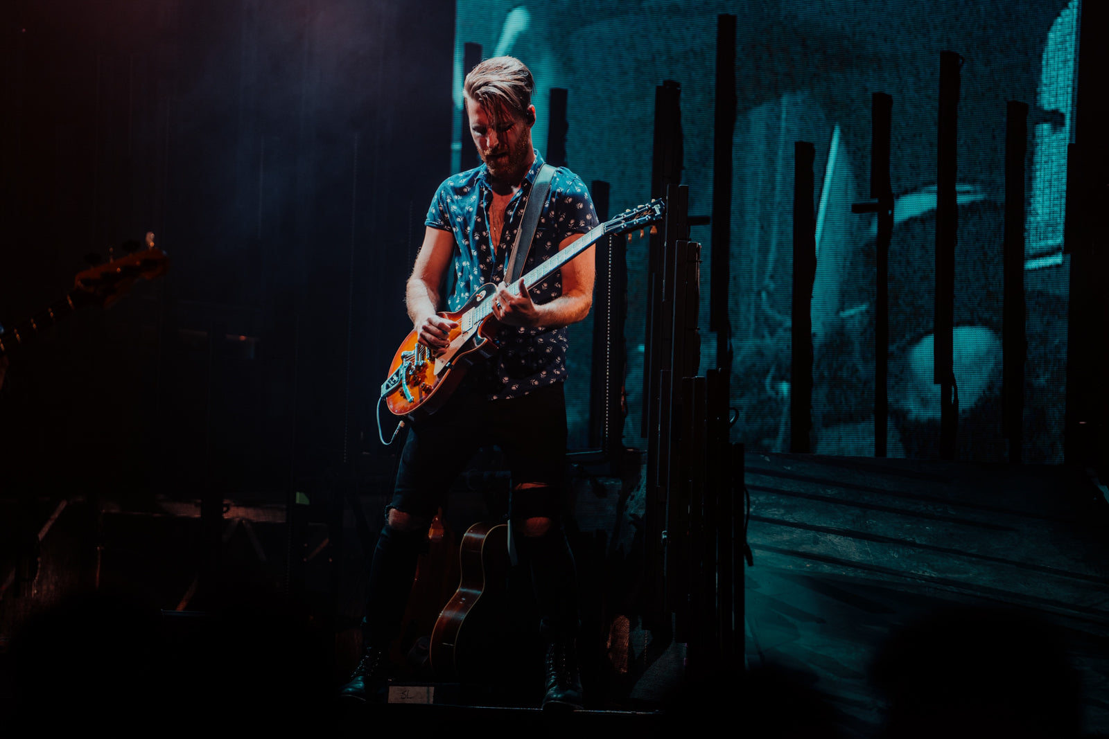 Person playing guitar on a stage with dim lighting